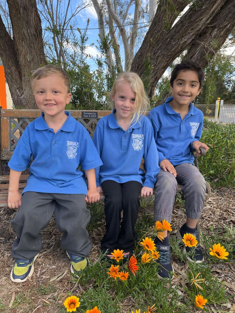 An image of three Kindergarten students in the flower garden