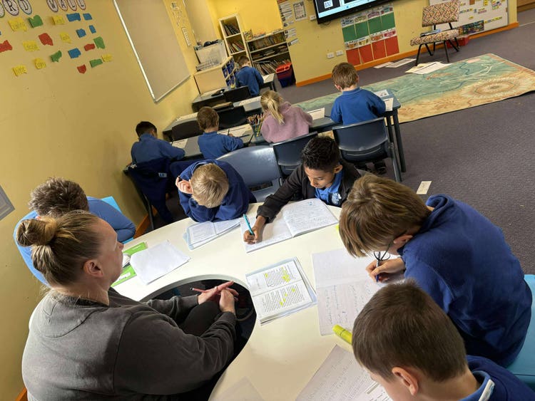 An image of a group of students being supported by a School Learning Support Officer (SLSO).