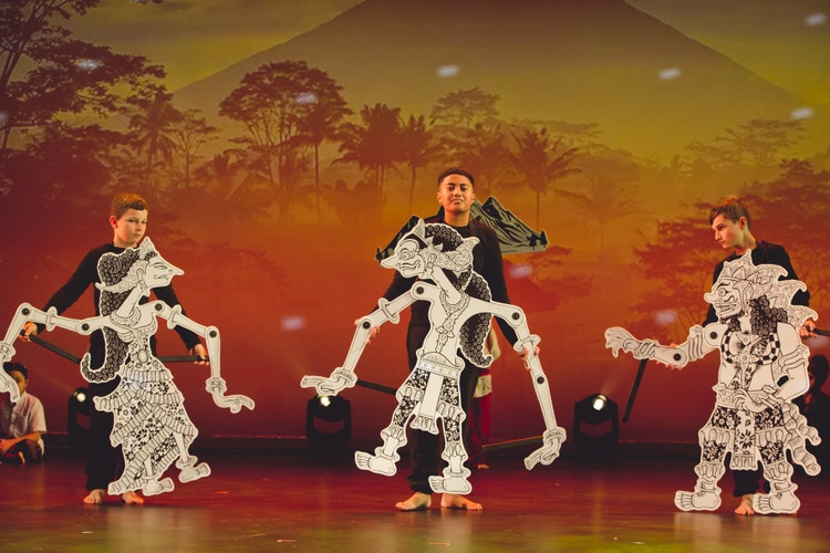 An image of three students performing with life size Indonesian puppets for our KROP Performance.